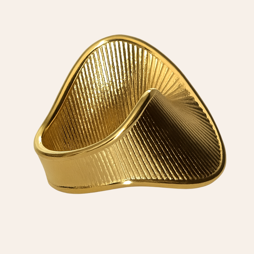 Gold triangular ring on a light beige background