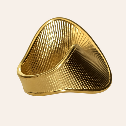 Gold triangular ring on a light beige background