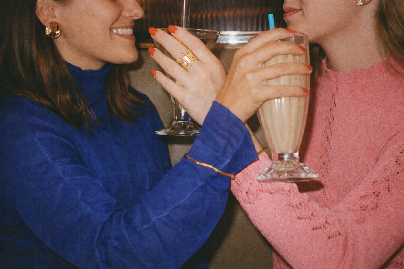 Two women enjoying drinks together, one holding a milkshake.