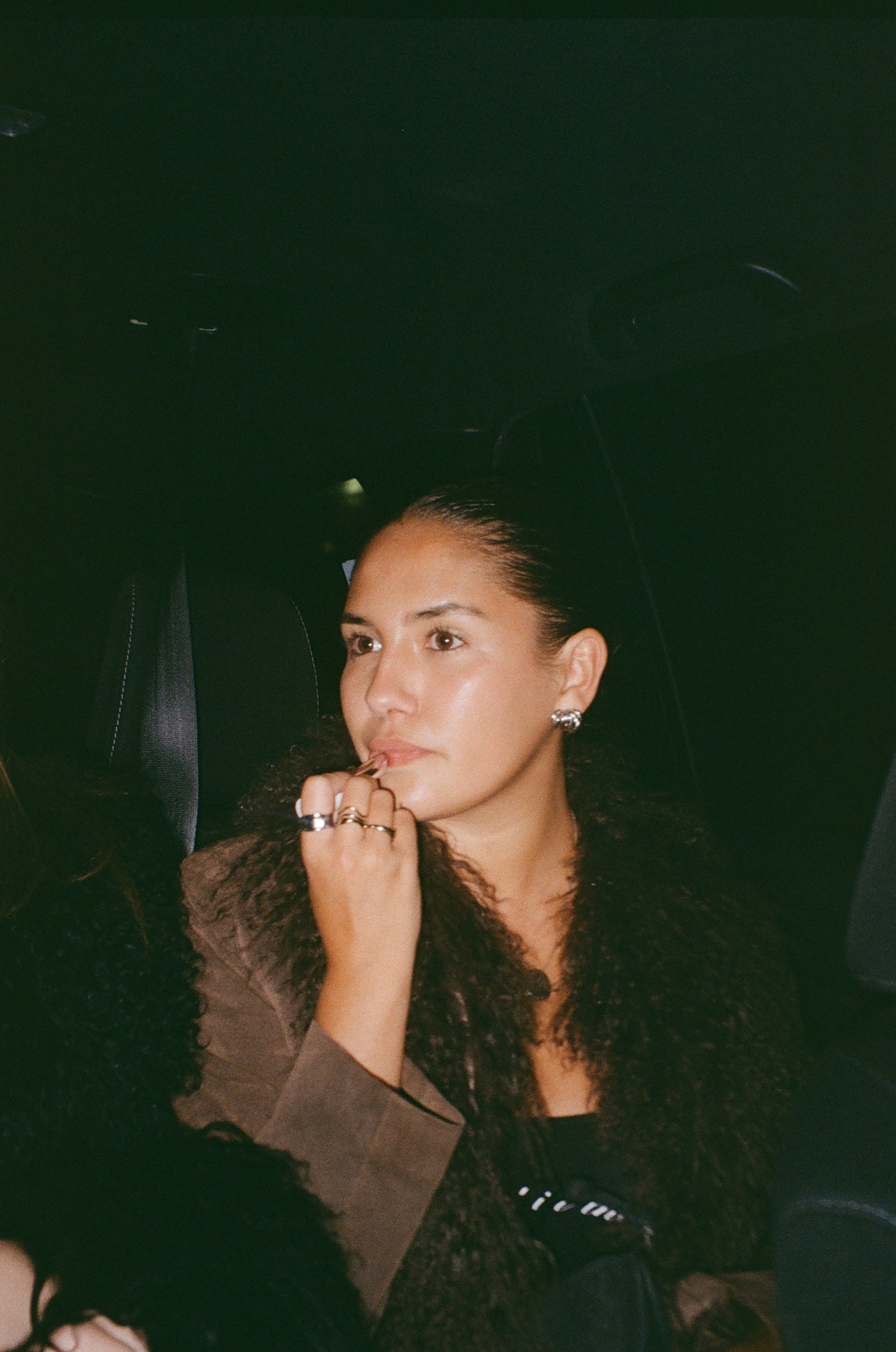 Person putting on lipstick in an NYC city cab wearing the Bailey and Olive Ring