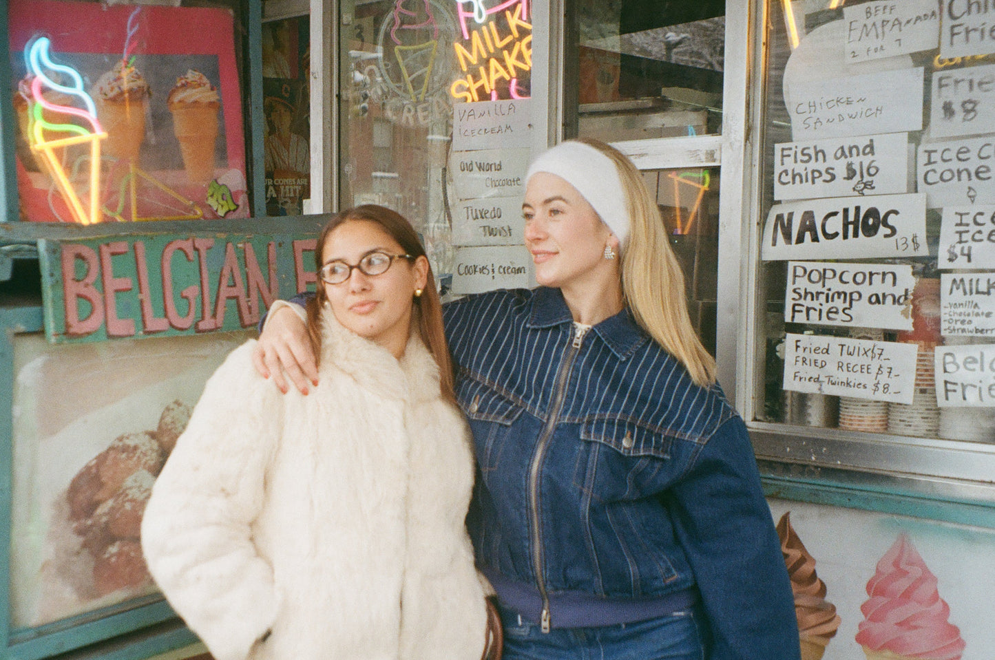 Two women standing in front of an ice cream shop with neon signs wearing the Vienna Earrings and Caprice Earrings
