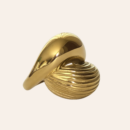Gold ring with a textured design on a light beige background